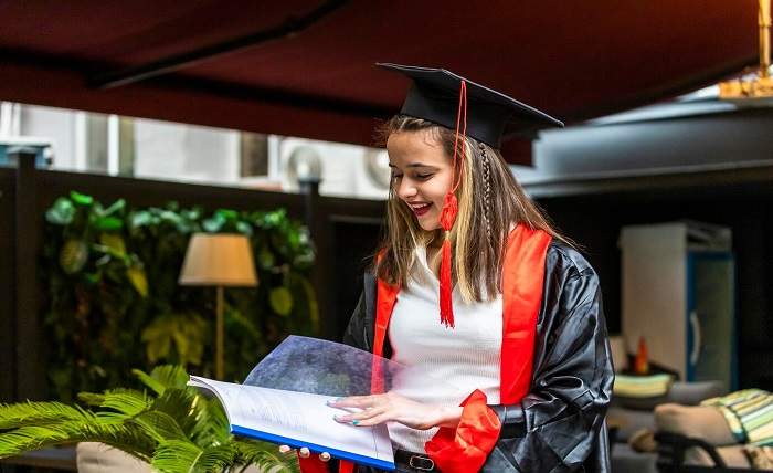 young student wearing graduation cape looking her notebook 114579 92485