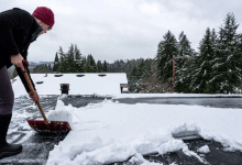 flat roofer clearing snow