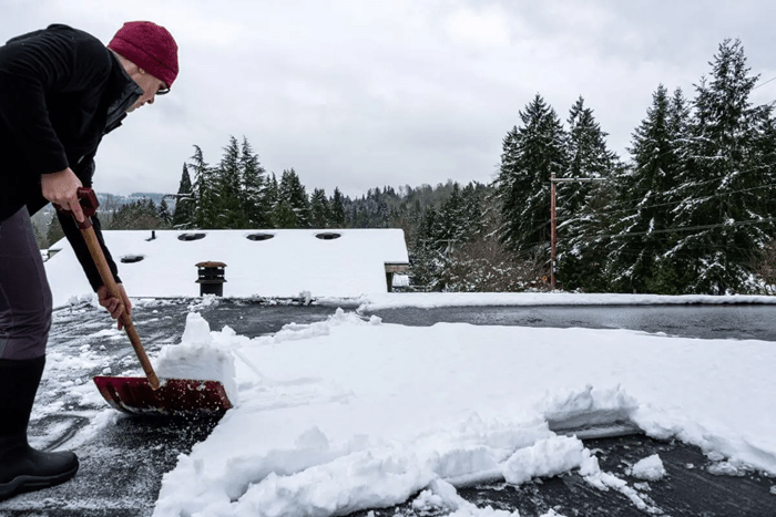flat roofer clearing snow